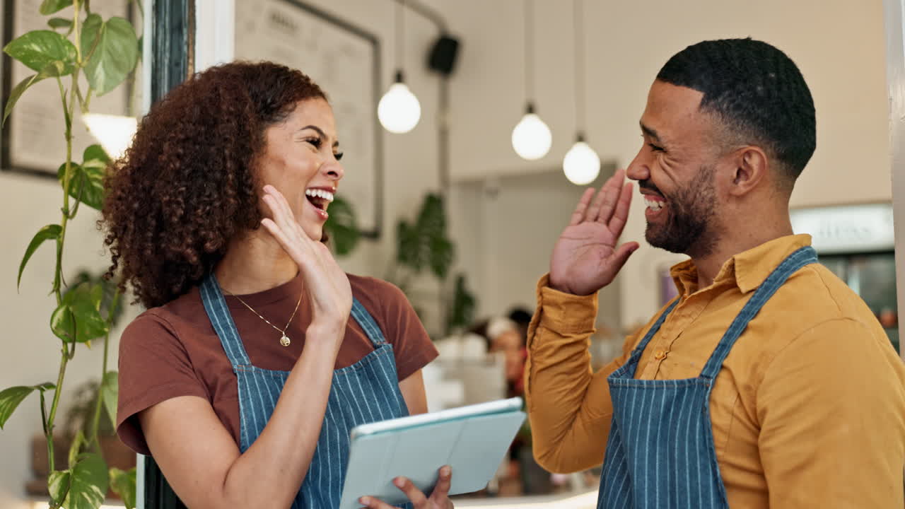 Two business owners celebrating success using a tablet