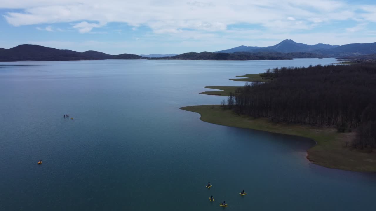 Flying over lake Plastira's shoreline and people riding water bikes