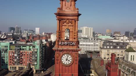 Drohnenflug-Aus-Der-Luft-Durch-Den-Zentralen-Torbogen-Des-Uhrturms-Des-Zufluchtsgebäudes-An-Der-Oxford-Road-Im-Stadtzentrum-Von-Manchester-Mit-Blick-Auf-Die-Umliegenden-Dächer