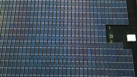 aerial rising top down of solar panel farm on roof of large warehouse. sunset time at dusk. renewable energy theme.