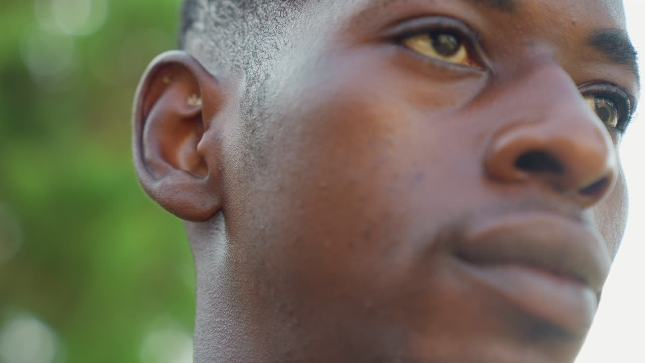 Black sport athlete closeup face contemplative outdoor portrait showing sweat and sunlight on skin, upward gaze, runner preparing for sprint, trainee cooling down, modellike profile, quiet