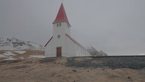 Iglesia-De-Vík-I-Myrdal,-Punto-De-Referencia-De-Islandia-En-Un-Día-Frío-Y-Nublado-De-Primavera,-Tiro-De-ángulo-Bajo-De-Paralaje