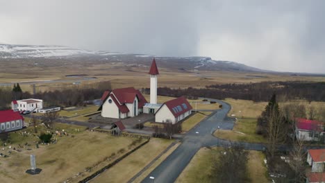 drone view of church in iceland with snowy mountains on background, orbit shot