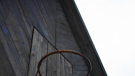 old rusty wooden house with a basketball net in a cloudy back in the backyard