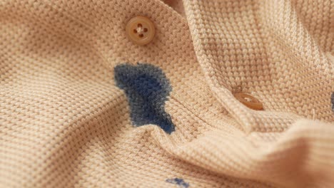 close up of a tan shirt with a blue ink stain