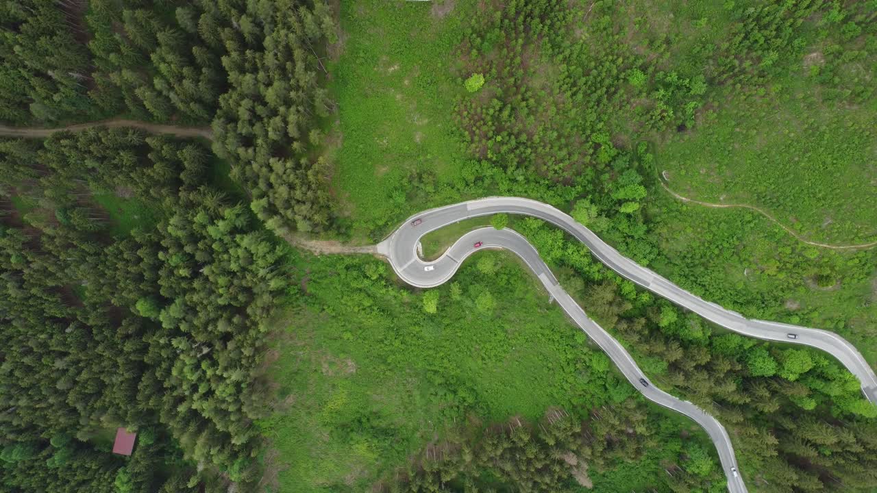 una toma aérea de un dron de 4k de coches conduciendo en una sinuosa carretera serpenteante