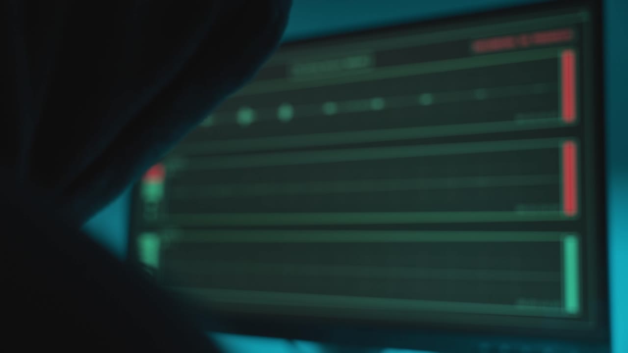 Hacker with black hoodie looking at computer monitor with audio recording app capturing sound remotely and secretly. Wiretapping and surveillance. Privacy breach. Dark web and corruption fraud crime