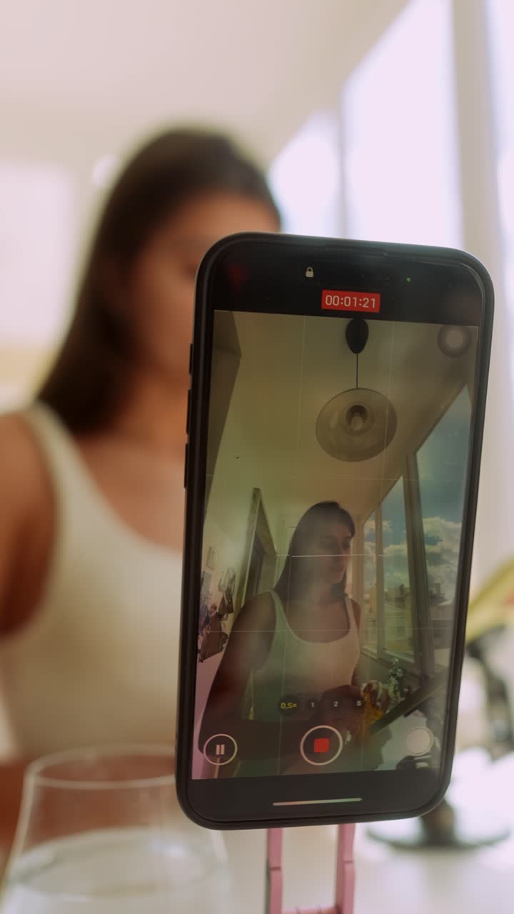 Giovane donna che registra un video con lo smartphone su un treppiede
