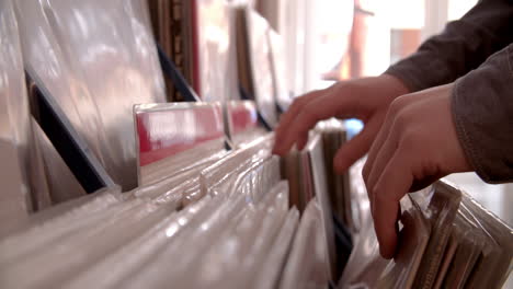 close-up of hands sorting through records at a record shop