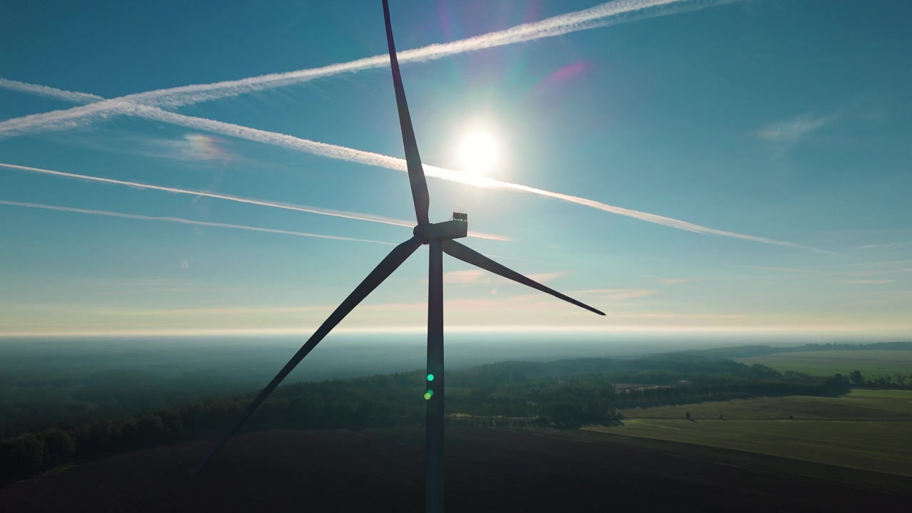 Renewable Wind Power Turbine With Sun Flare Above Countryside Horizon