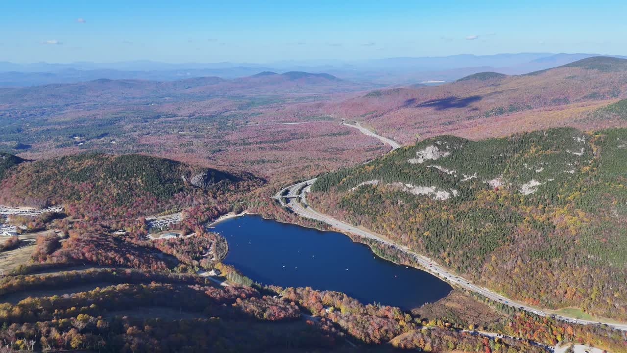 Vista drone del lago Echo e dell'autostrada I-93 che si snoda attraverso la foresta autunnale nelle White Mountains, New Hampshire, USA
