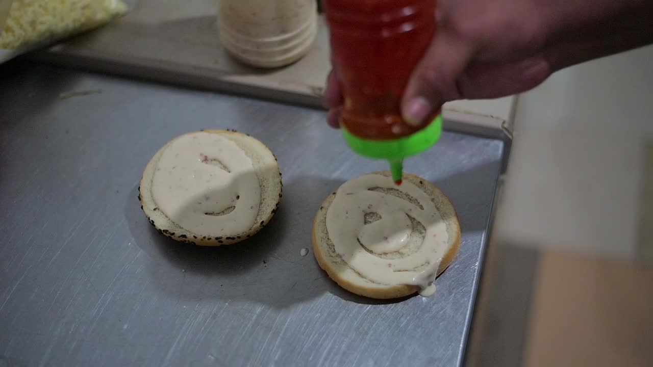 el chef cubriendo la hamburguesa redonda con ketchup de tomate fresco
