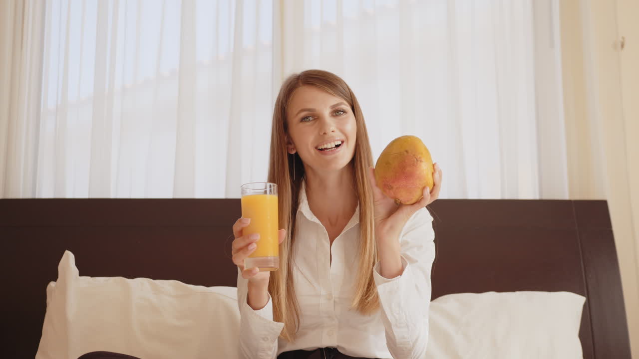 오렌지 주스와 망고로 아침 식사를 즐기는 여자