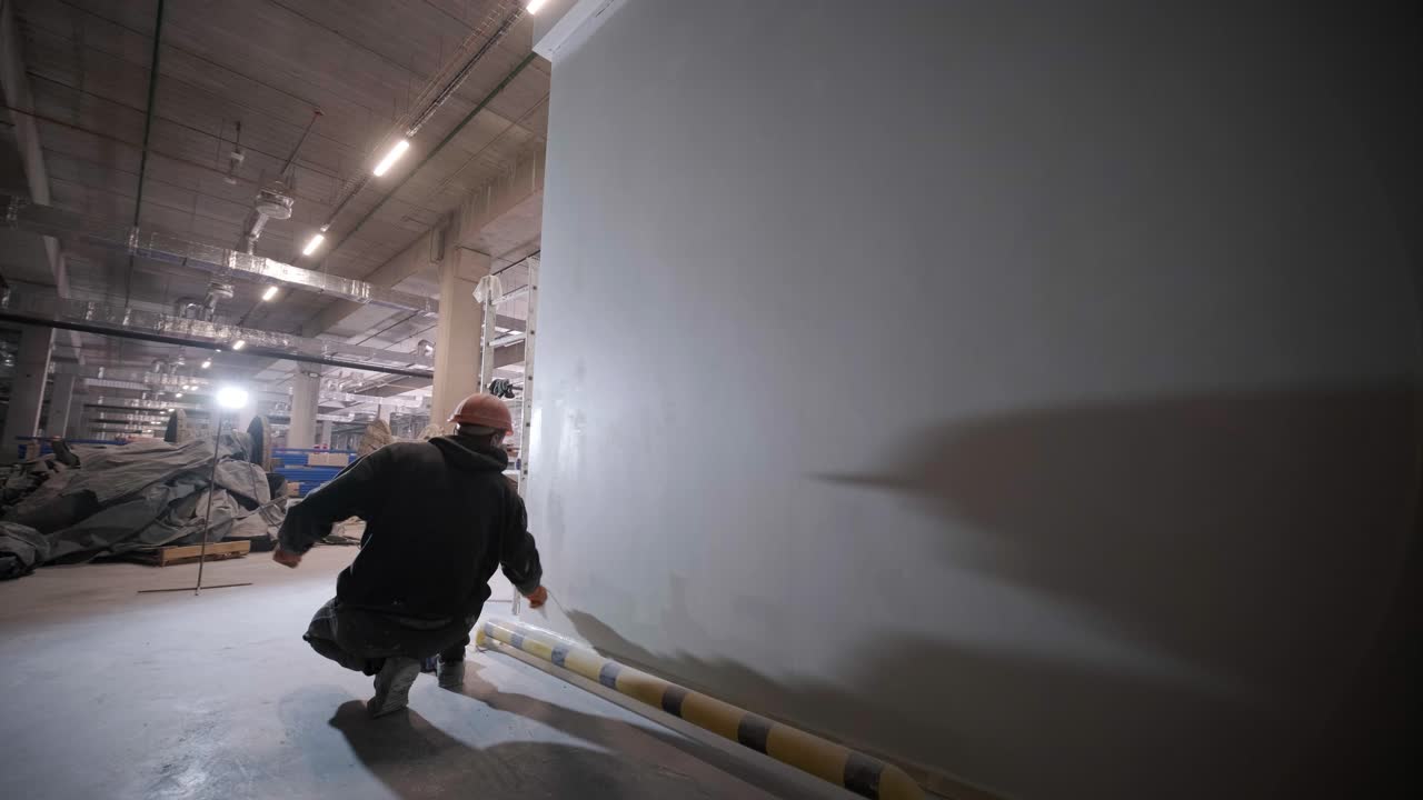 Il pittore sta dipingendo una parete in una grande fabbrica