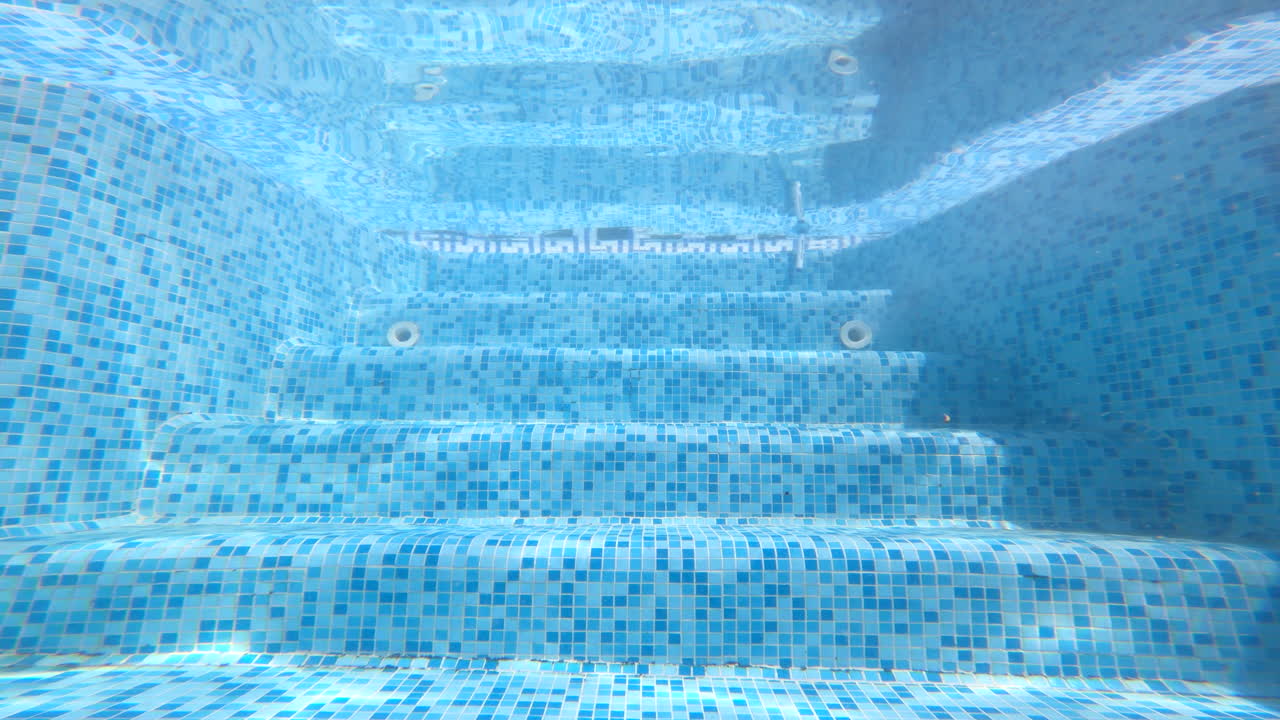 Underwater view of a swimming pool with a blue mosaic tile pattern