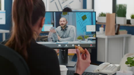 executive manager eating delivery takeaway pizza during online videocall conference meeting