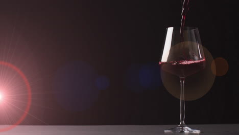 compuesto de vino tinto que se vierte en un vaso sobre un fondo rojo oscuro