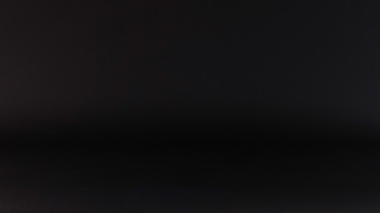 una pelota púrpura rodando a través de una superficie oscura