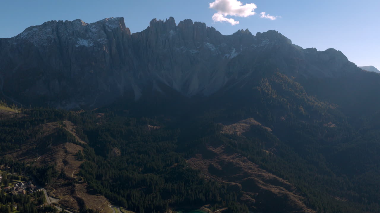 Cinematic aerial view of Dolomites Italy at sunrise, rugged rocky peaks above lush alpine hills and scattered chalets, serene mountain travel landscape nature scenery