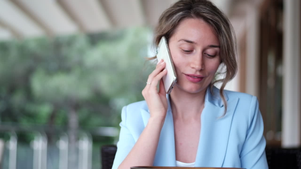 Brunette woman in a blue blazer talking on the phone at a restaurant