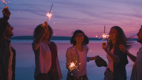 amigos celebrando el atardecer junto al lago con sparkler