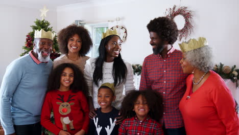 Portrait-Of-Multi-Generation-Family-Wearing-Paper-Hats-Celebrating-Christmas-At-Home-Together