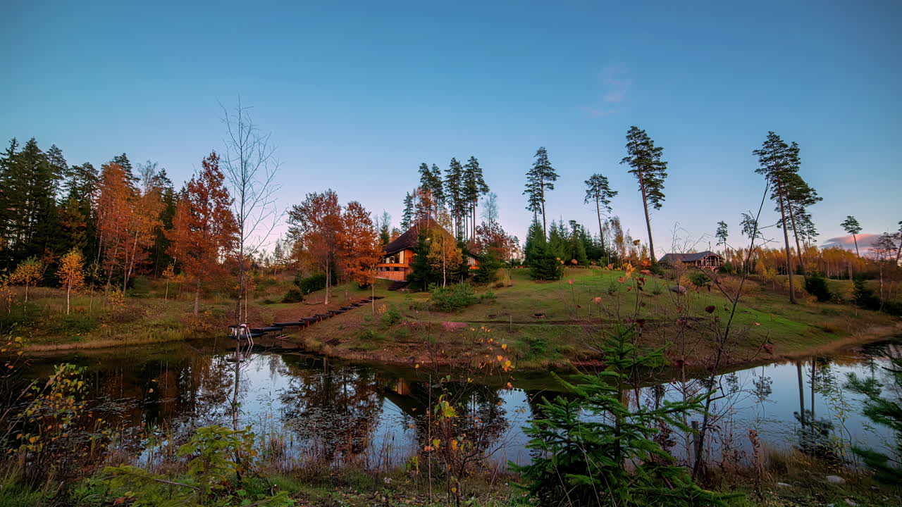 Casa in legno nella foresta con un lago nelle vicinanze, ripresa in time lapse in movimento.