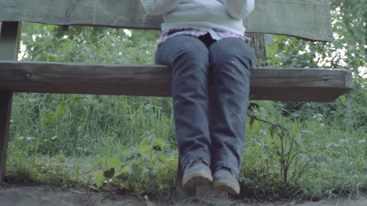 Woman sitting on wooden bench in countryside medium panning shot