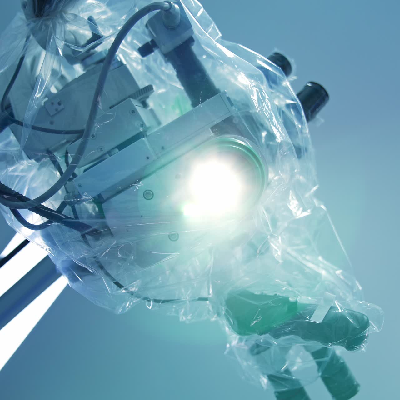 Bright light coming from a high-precise microscope apparatus covered with plastic in surgery room. View from below