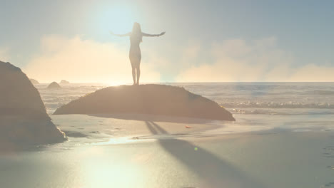 Animation-of-glowing-light-over-woman-standing-on-rock-by-sea