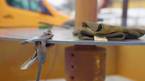 abrazadera de tierra utilizada para soldar en una mesa redonda de acero con guantes sucios