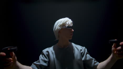 un tipo jugando a un juego de realidad virtual con gafas futuristas en una habitación oscura.