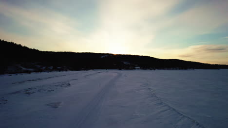 Flying-drone-above-a-frozen-lake-in-canada-at-golden-hour