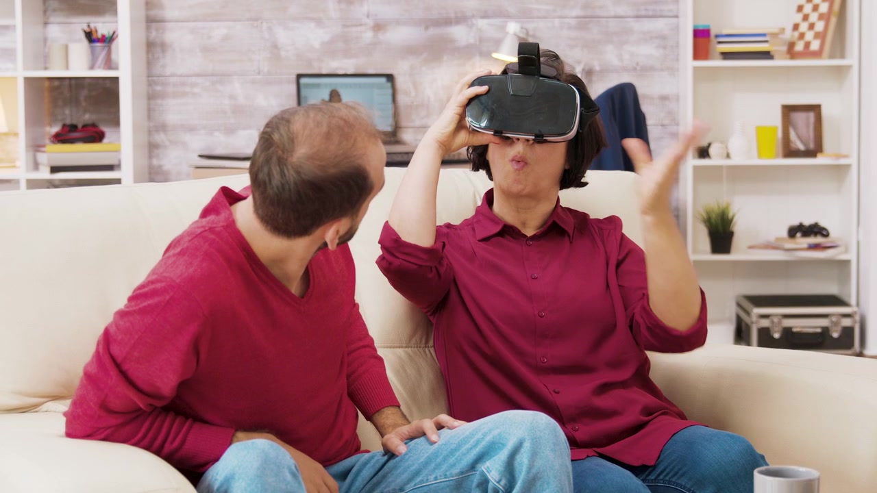 Jonge man helpt oudere vrouw met het gebruik van een virtual reality-headset thuis
