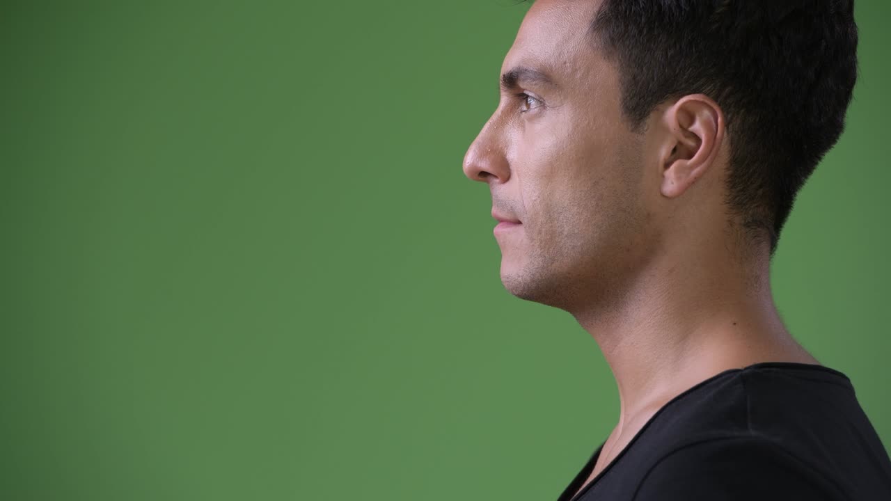 joven y guapo hombre hispano contra un fondo verde