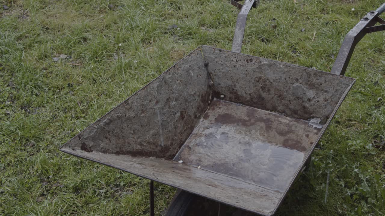 Vecchia carriola d'acciaio arrugginita sotto la pioggia 4K