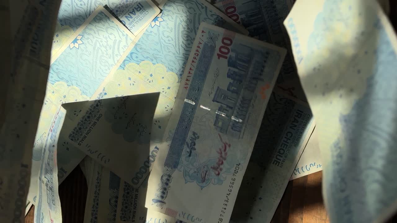 Showing banknotes of rials in Iran Tehran blue color USD USA wooden table hurl fling forceful bundle currency compare 100 dollar versus financial fall inflation economy finance investment sell wealth