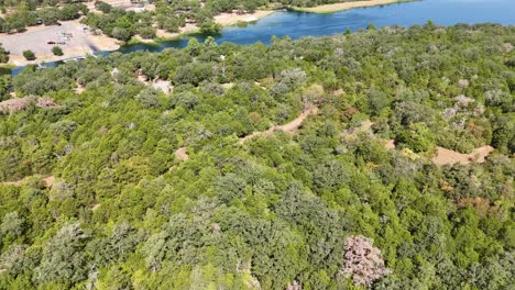 Moviéndose-Rápidamente-Sobre-Una-Gran-Sección-De-árboles-Que-Da-Paso-A-Una-Pequeña-Cabaña-Para-Acampar-Cerca-De-La-Entrada-De-Un-Lago-Que-Tiene-Una-Rampa-Para-Botes-Y-Una-Costa-Y-Espacio-Recreativos.