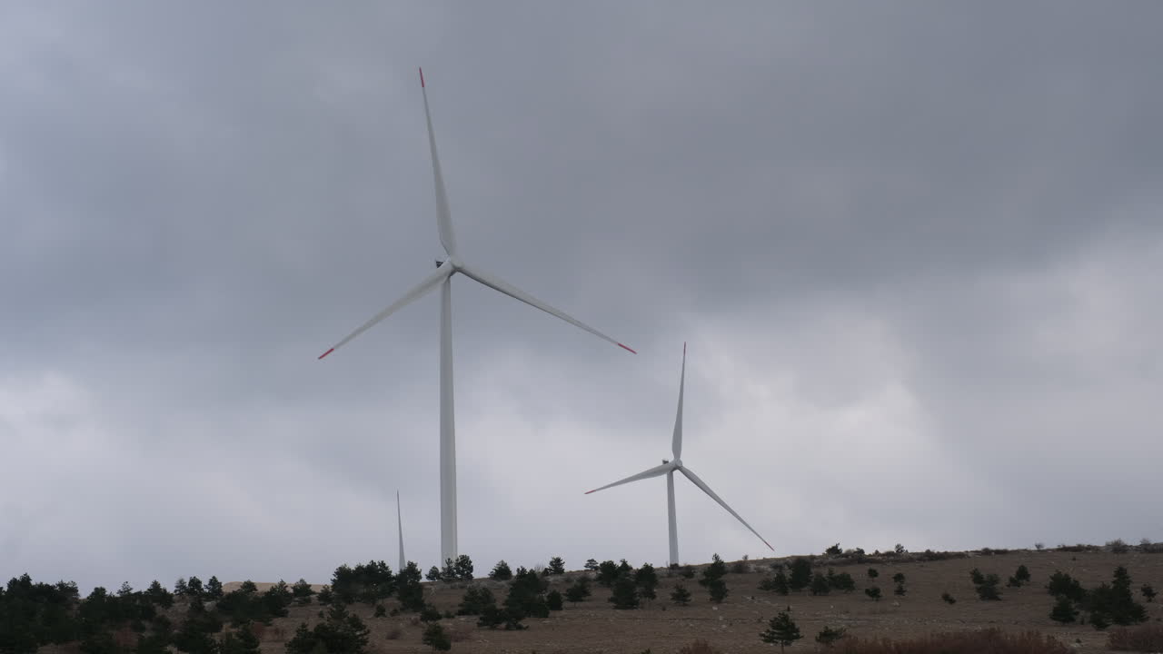 A large wind turbine plant. Sustainable and renewable green energy from the wind. Turbines arranged on a mountain plateau. Windy weather before the storm.