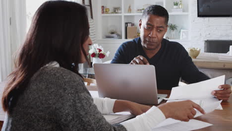 african american male financial advisor discussing documents with a woman at her home, close up