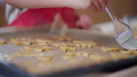 close-up of cookies and spreading them with glaze made of raw eggs