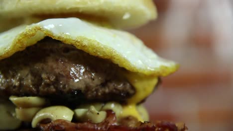 primer plano de una hamburguesa doble con tocino, cebolla, champiñones y huevo frito