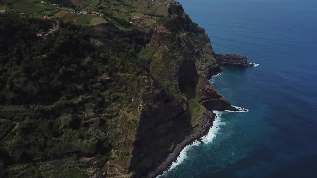 Goditi splendide riprese con drone di onde che si infrangono contro una montagna maestosa a Madeira