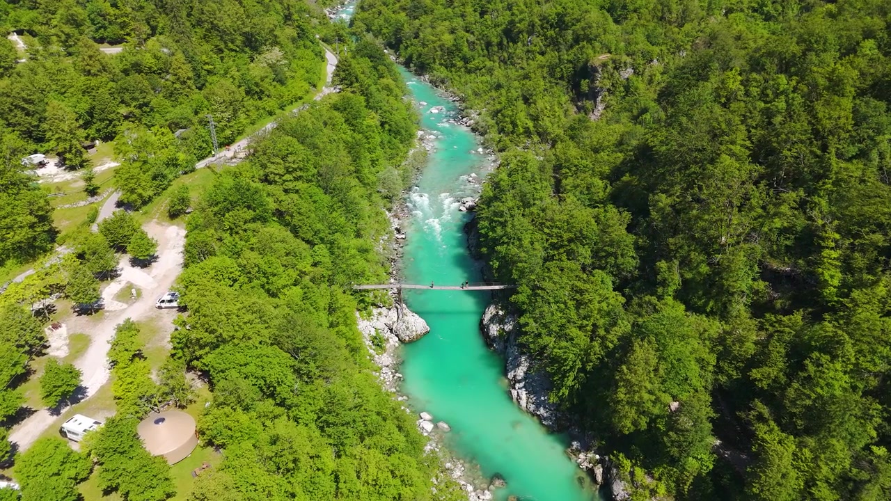 Ponte sospeso che attraversa il fiume color smeraldo Isonzo nella regione boscosa di Posočje, ripresa con drone in orbita sinistra.