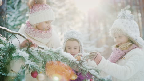 a mother with two daughters adorns a green spruce in a fairy-covered snowy forest sunlight makes its