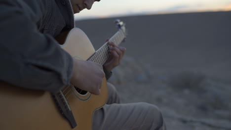 Close-Up-shot-a-musician-playing-guitar-in-the-desert