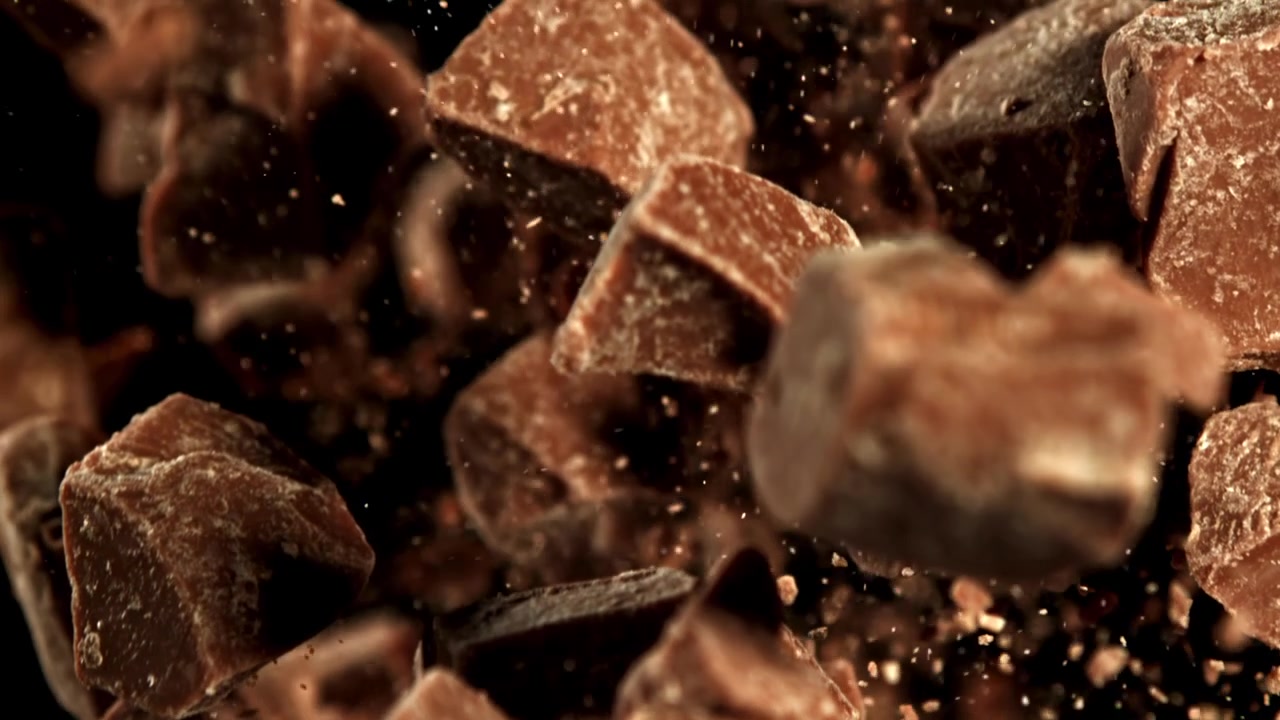 Pezzi di cioccolato che cadono in super slow motion su sfondo nero