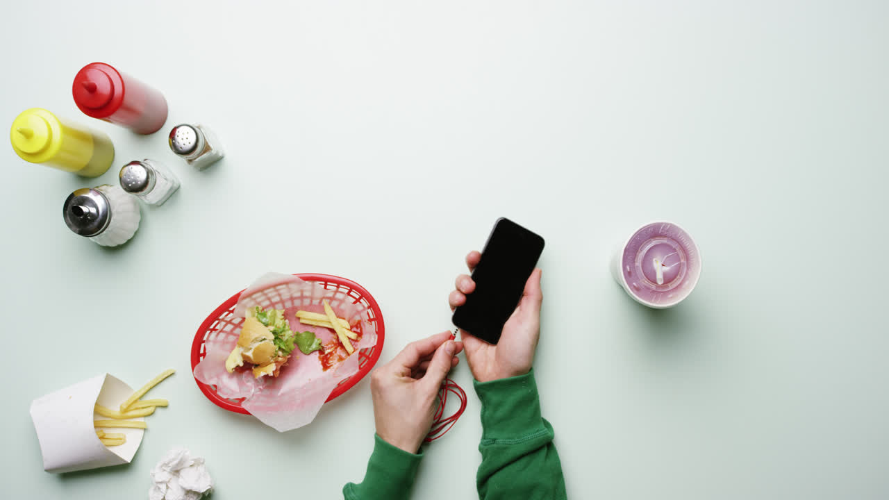 vista superior hombre conectando auriculares a teléfono móvil en un restaurante de comida rápida americano manos desde arriba - dragón épico rojo