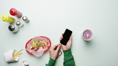 Vista-Superior-Del-Hombre-Conectando-Auriculares-Al-Teléfono-Móvil-En-El-Restaurante-De-Comida-Rápida-American-Diner-Con-Las-Manos-Desde-Arriba---Dragón-épico-Rojo