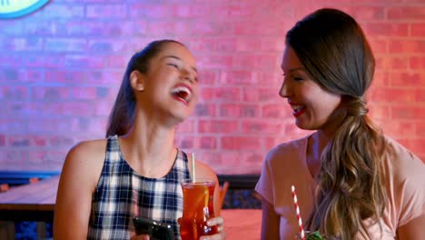 friends taking selfie on mobile phone while having cocktail